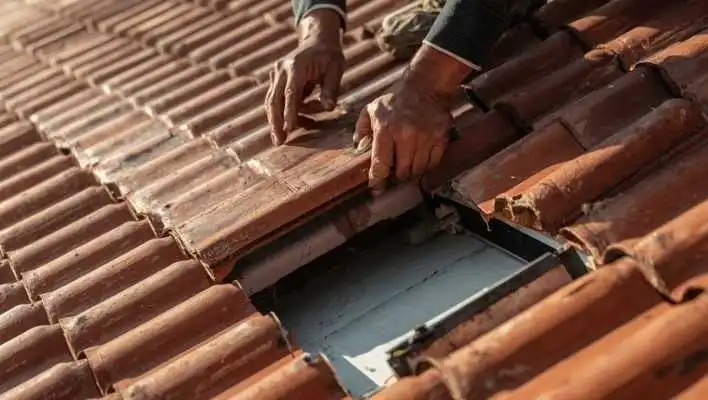 Roof inspector lifting clay tiles to check hidden underlayment condition in Chino Valley AZ before monsoon season